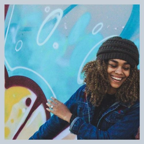 CREATIVE ARTS. Woman in front of a bright painting.