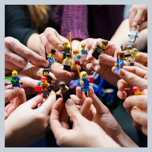 Volunteers. A bunch of hands holding lego people.