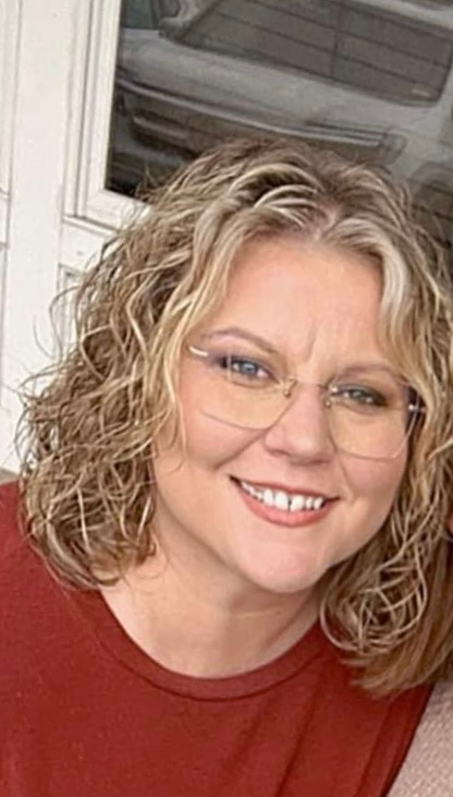 Woman in red shirt and glasses smiling.