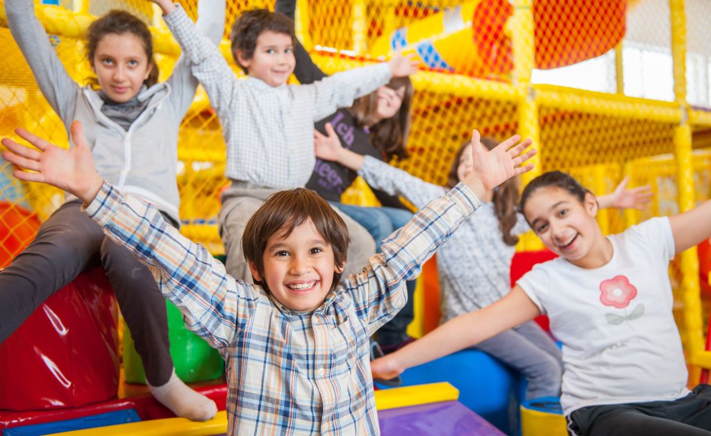 Excited children with arms raised playing no-equipment indoor youth group games